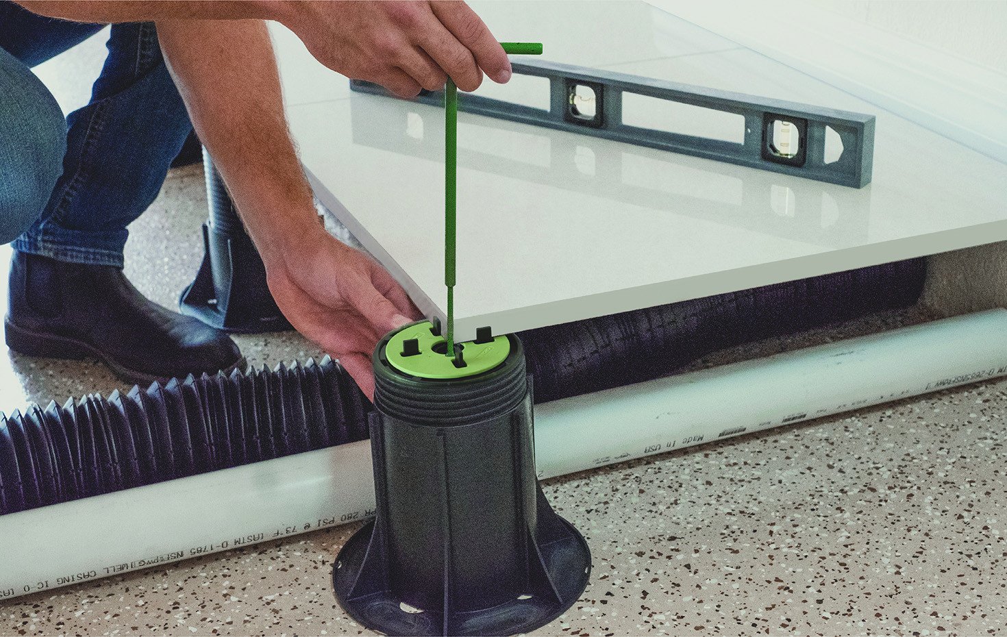 Un instalador ajusta un pedestal para crear una base precisa, nivelada y estable para pavimentos exteriores elevados con baldosas.