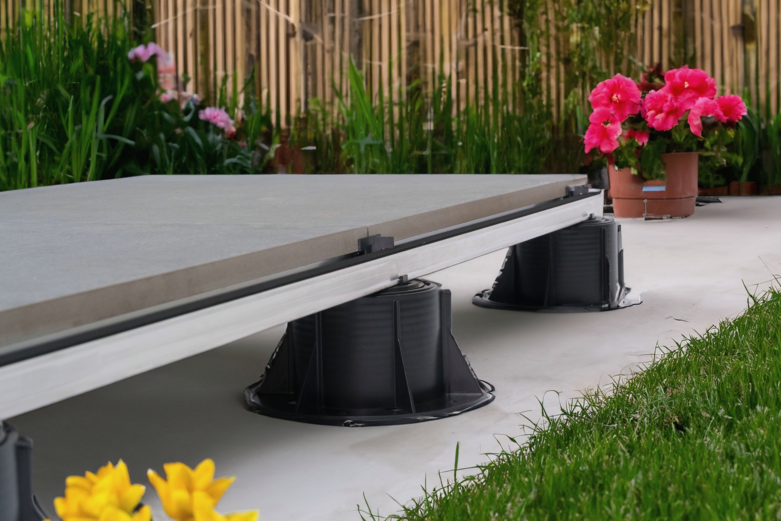Terrasse surélevée sur plots réglables Des dalles extérieures posées sur des plots réglables créent un système de terrasse surélevée plat, durable et flexible.